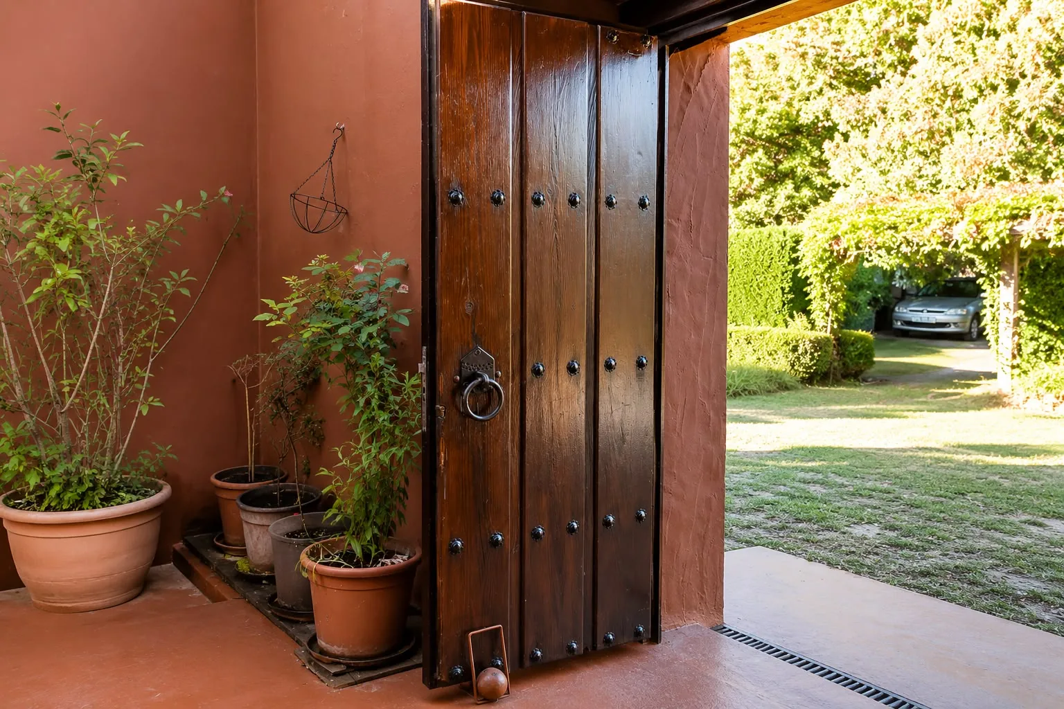 Puerta de entrada de madera maciza barnizada con tachones de forja