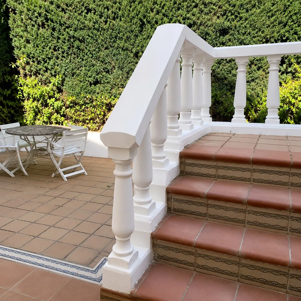 Escalera exterior con balaustrada blanca y peldaños de barro